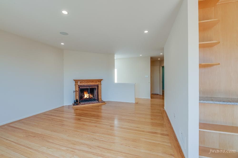 Open plan room with hardwood floors, built-in shelving, and a fireplace