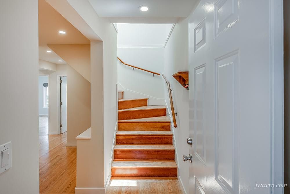 Entry hall with hardwood stairs and a handrail leading to the upper level
